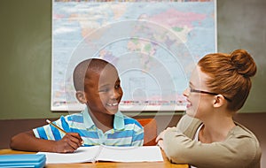 Teacher assisting little boy with homework in classroom