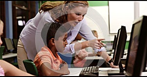 Teacher assisting school kids on personal computer in classroom
