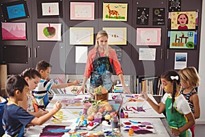 Teacher assisting schoolkids in drawing class