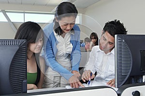 Teacher Assisting Students In Computer Lab