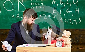 Teacher with beard, father teaches little son in classroom, chalkboard on background. Educational games concept. Boy