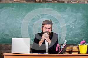 Teacher bearded mature schoolmaster listening with attention. Teacher formal wear sit at table classroom chalkboard