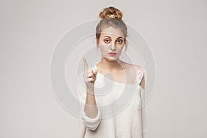 Teacher blonde woman finger up and looking seriously at camera.