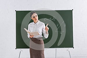 Teacher with book and chalk pointing