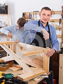 Teacher and boy chiselling a wooden bench in workshop