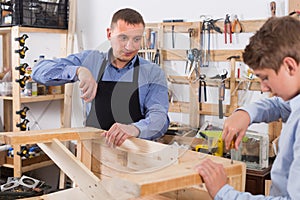 teacher and boy chiselling a wooden bench in workshop
