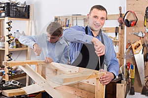 teacher and boy chiselling a wooden bench in workshop