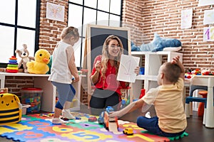 Teacher with boy and girl sitting on floor having maths lesson at kindergarten