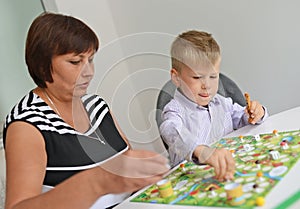 Teacher and boy playing with table game.