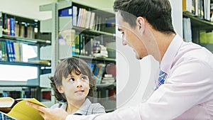 teacher and boy student learn with book with bookshelf background