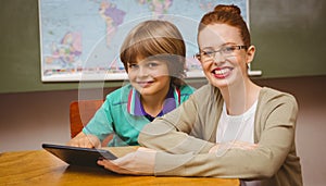 Teacher and boy using digital tablet in classroom