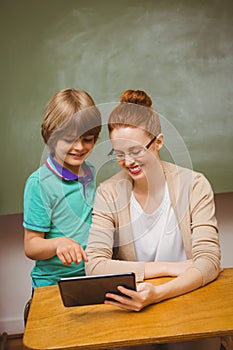 Teacher and boy using digital tablet in classroom