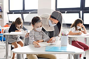 Teacher and children with face mask back at school after covid-19 quarantine and lockdown.