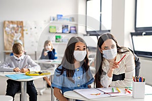 Teacher and children with face mask back at school after covid-19 quarantine and lockdown.