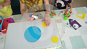 Teacher with children sitting at the table and doing handmade items.