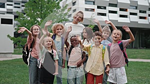 Teacher with children smiling and waving hands on schoolyard