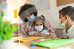 Teacher with children wearing face mask in preschool classroom during corona virus pandemic