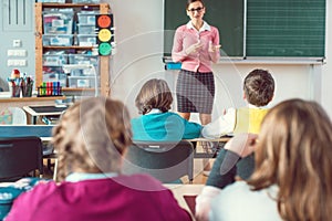 Teacher in class with fourth grade students in front of black board