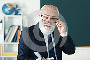 Teacher in the classroom near the blackboard is teaching a lesson. Professor at the university is giving a lecture.