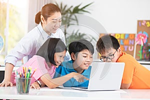 Teacher and Cute Asian children using laptop computer together.