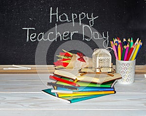 Teacher Day. Flowers and gift; copybooks on the teacher's desk.