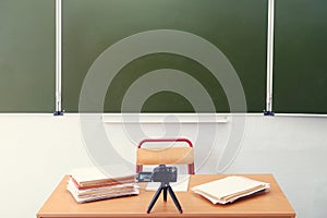 Teacher desk, blackboard and a video camera filming an online lesson, no people. Empty school table, nobody photo