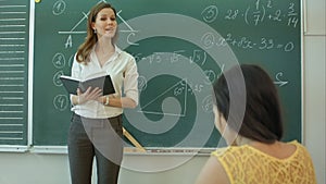 Teacher or docent or educator giving while lesson in front of a blackboard or board a sheet of paper and educate or