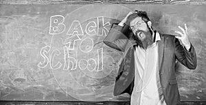 Teacher or educator stands near chalkboard with inscription back to school. Teacher unhappy shouting hysterically face