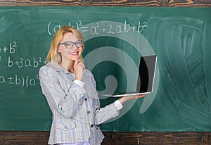 Teacher elegant lady with modern laptop surfing internet chalkboard background. Woman teacher wear eyeglasses holds