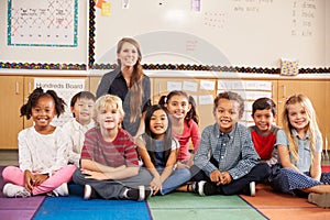 Teacher and elementary school kids sitting on classroom floor