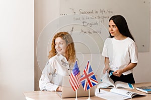 Teacher of english asks student in white class. 2 girls student answers to teacher. Working in group. Study english and