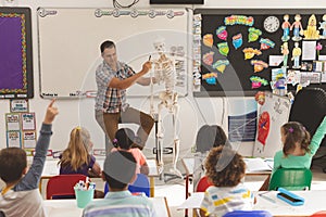 Teacher explaining about human skeleton in classroom at school