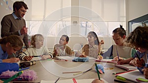 Teacher explaining lesson to schoolchildren. Students writing in exercise books