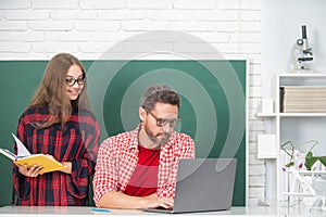 Teacher explains lesson to school child. Elementary school kids learning. School child using laptop.