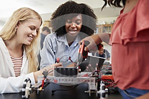 Teacher With Female Pupils Building Robotic Vehicle In Science Lesson