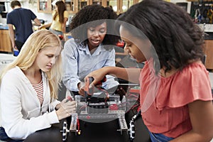 Teacher With Female Pupils Building Robotic Vehicle In Science Lesson