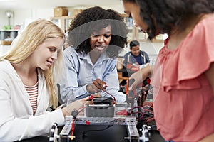 Teacher With Female Pupils Building Robotic Vehicle In Science Lesson