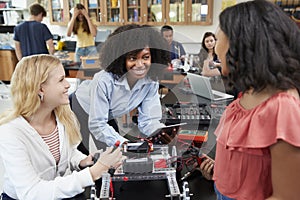 Teacher With Female Pupils Building Robotic Vehicle In Science Lesson