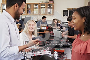 Teacher With Female Pupils Building Robotic Vehicle In Science Lesson