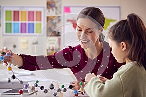 Teacher And Female Student In School Science Class Studying Molecular Model