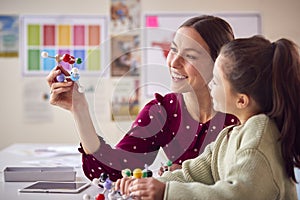 Teacher And Female Student In School Science Class Studying Molecular Model