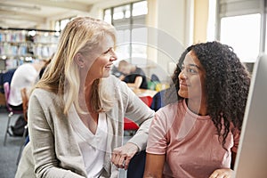 Teacher And Female Student Work On Computer In College Library