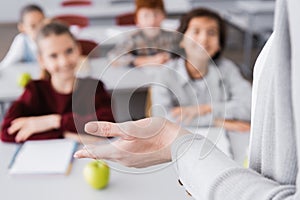 teacher gesturing during lesson near schoolkids