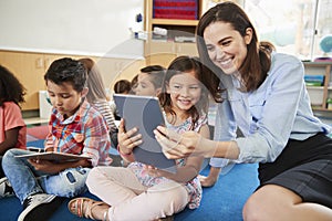 Teacher and girl in elementary class using tablet computers