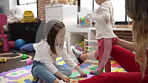 Teacher with girls playing with maths puzzle game and construction blocks at kindergarten