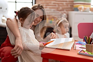 Teacher with girls smiling confident cutting paper at kindergarten