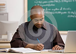 Teacher grading papers in school classroom