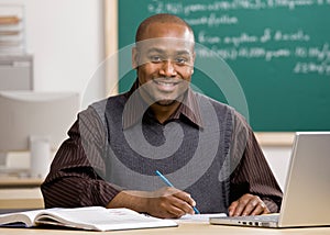 Teacher grading papers in school classroom