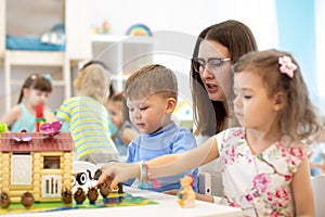 Teacher and group of kids buiding toy house with constructor in craft class