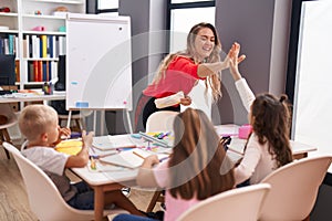 Teacher and group of kids having space lesson high five at classroom